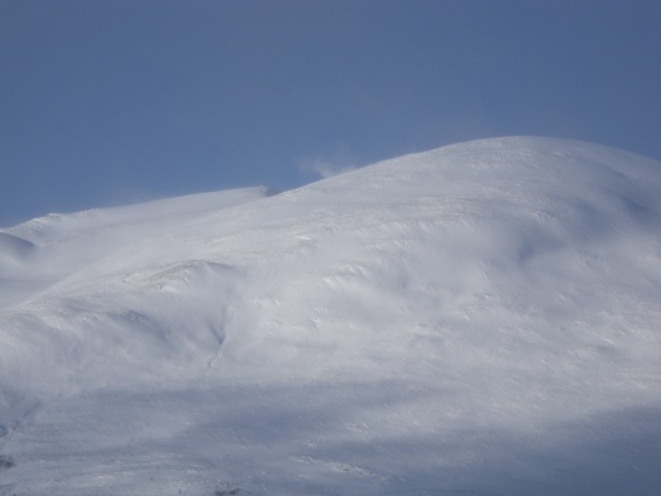 Plumes of windblown snow kicking off high ridgelines